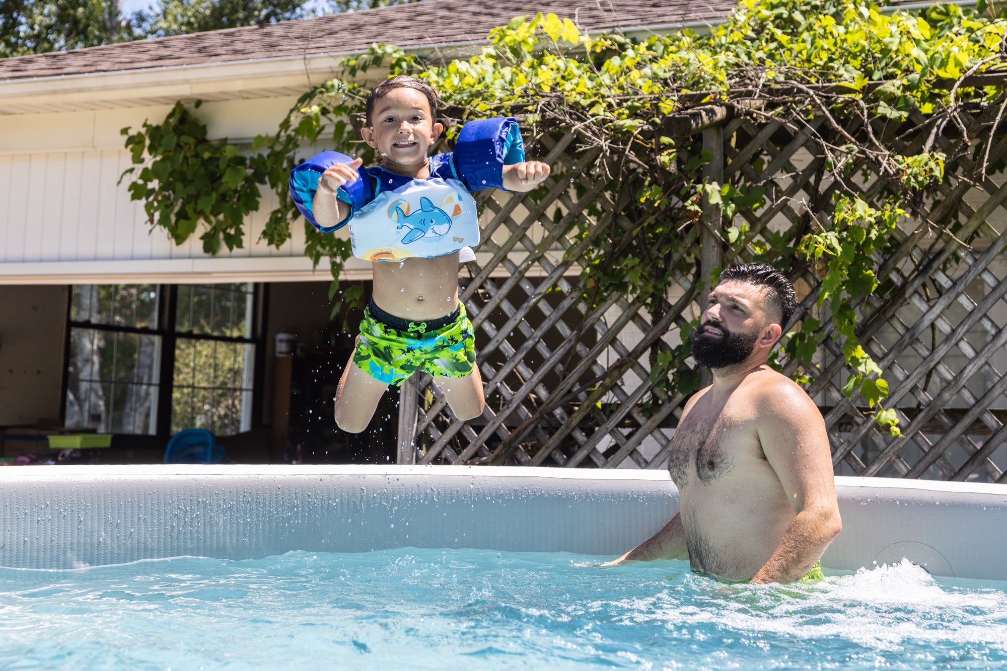 Father and child playing in a Perfect Pool with the child leaping into the water, showing minimal ground preparation and instant enjoyment