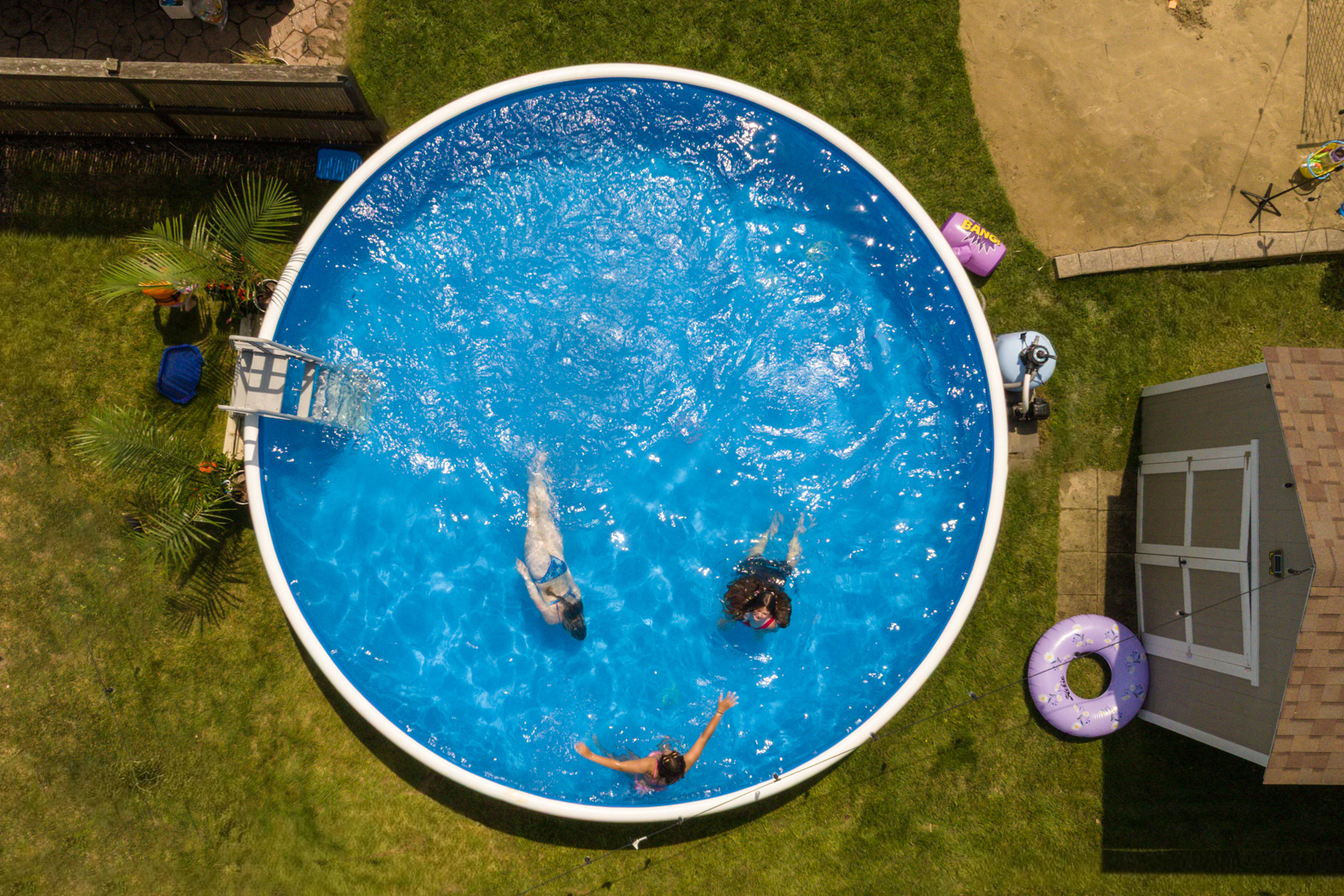 Aerial view of a round Perfect Pool with people swimming in a backyard setting.