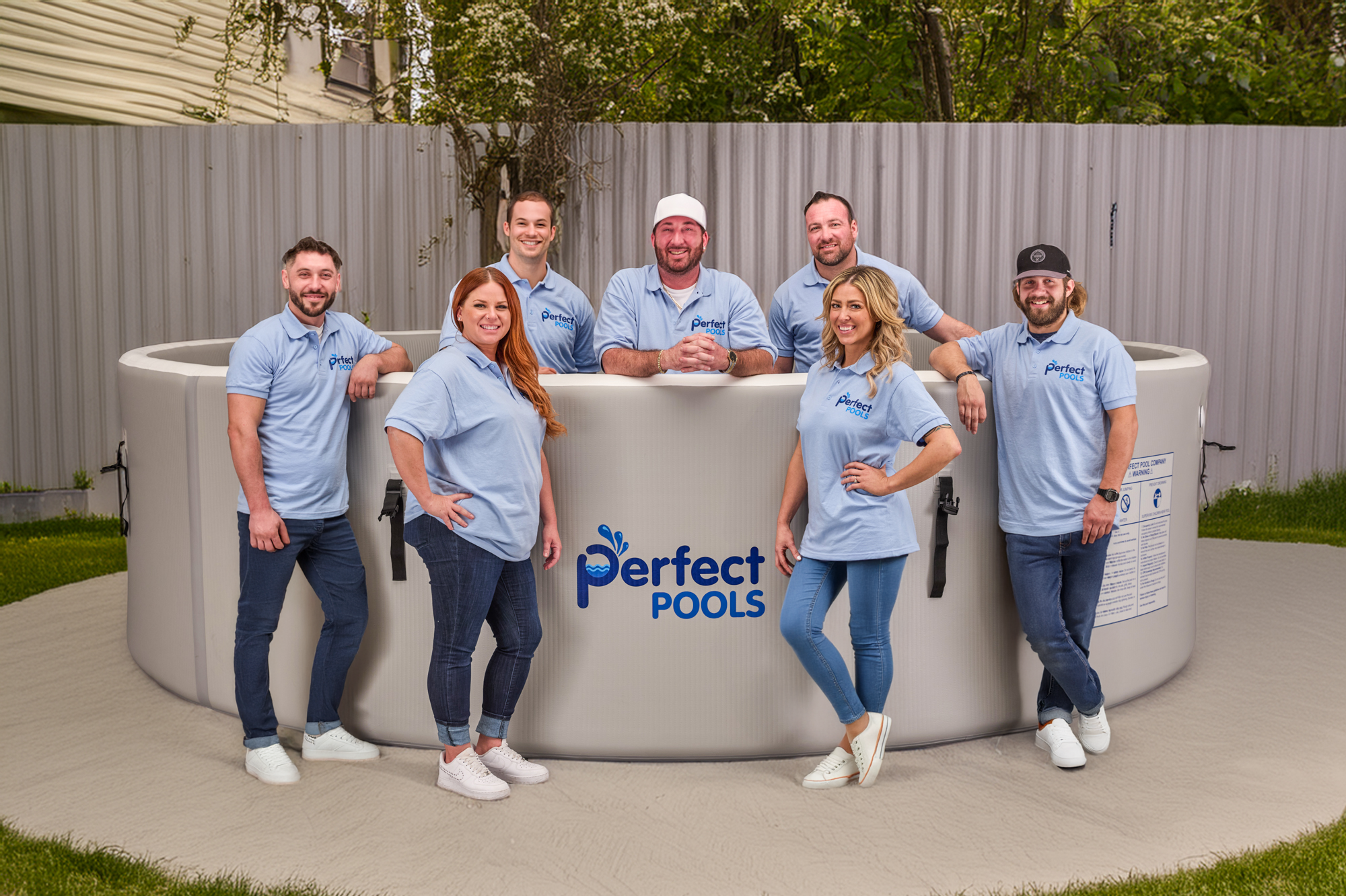 Perfect Pools Company team standing together in branded polo shirts behind a Perfect Pool, highlighting the people behind the business